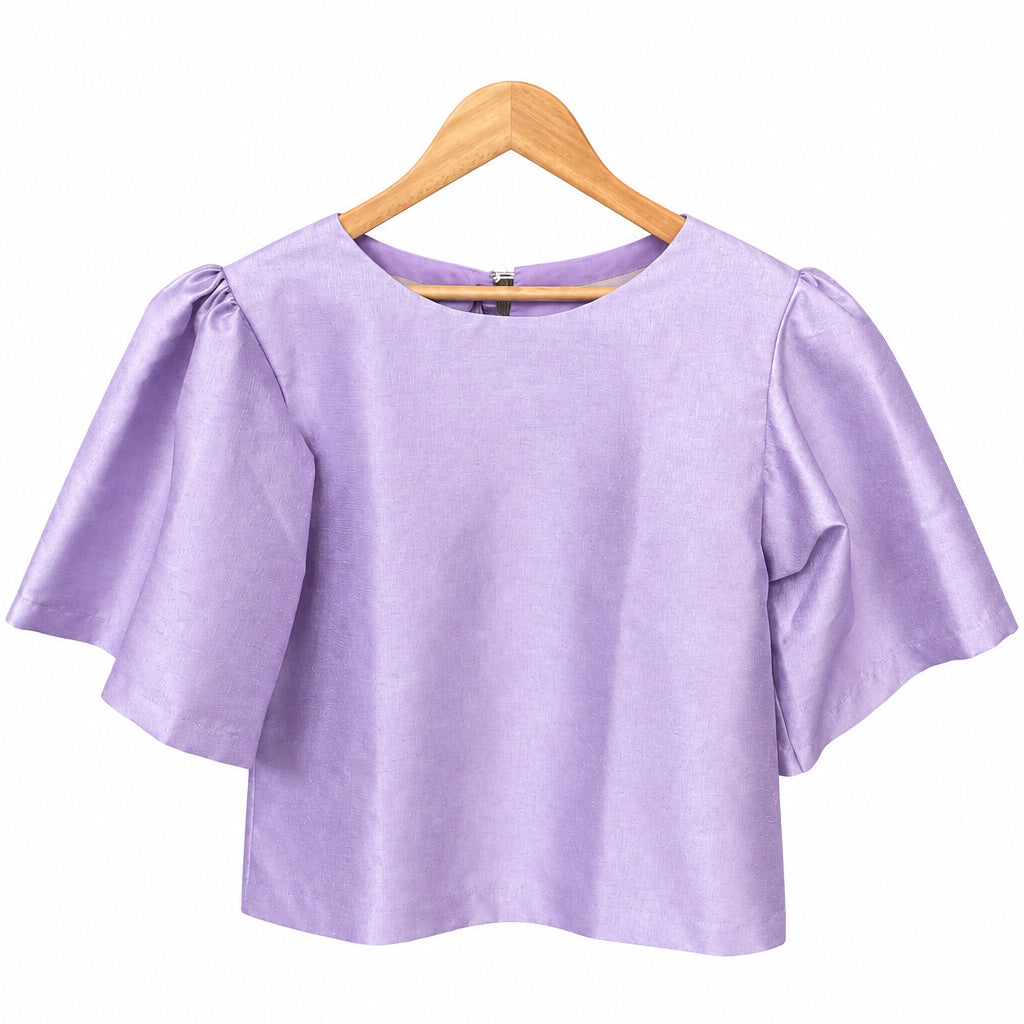 A lavender purple short-sleeve blouse with puffed sleeves, displayed on a wooden hanger on a blue stand in what appears to be a workshop or closet.